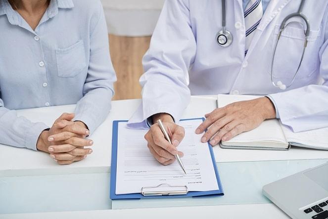 médico realizando consulta médica, explicando detalhes para a paciente mulher ao seu lado