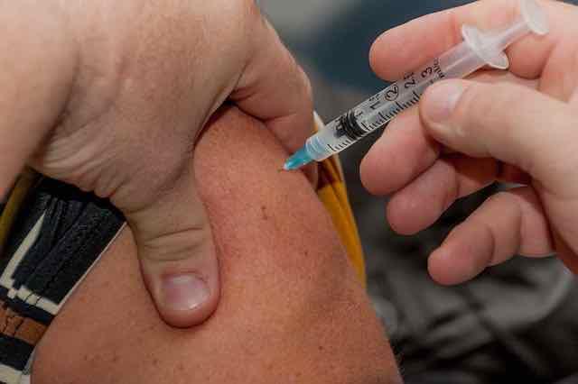 close de vacina sendo injetada em braço de homem