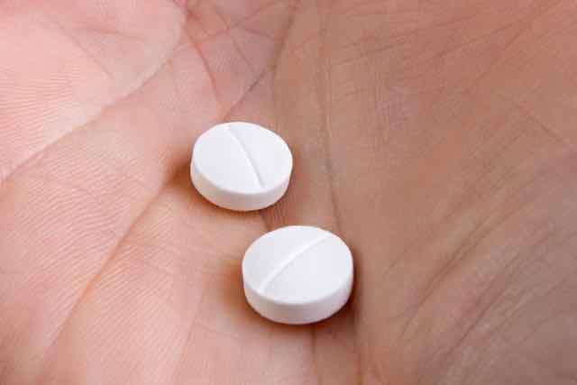 mão segurando duas pilulas de remedio