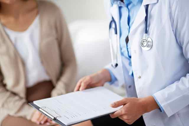 médica segurando ficha na consulta com paciente