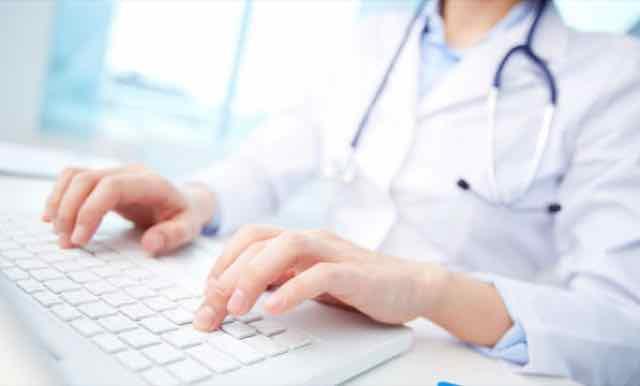 médico digitando no computador