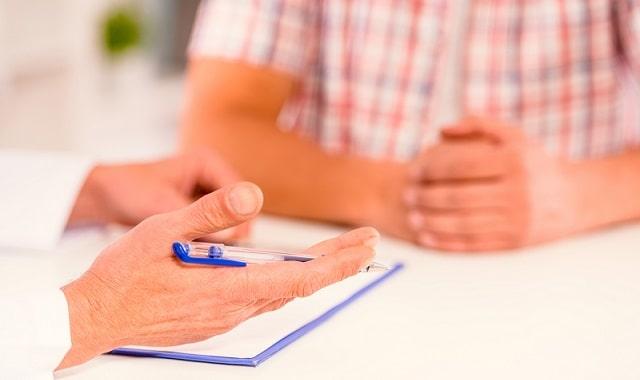 médico orientando homem com hiperplasia prostatia benigna; mãos em foco