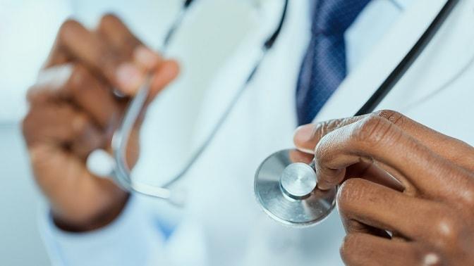 médico segurando estetoscópio, foco nas mãos, representando as inovações médicas de 2020