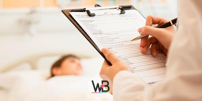 médico escrevendo em prontuário de paciente internada com câncer de mama
