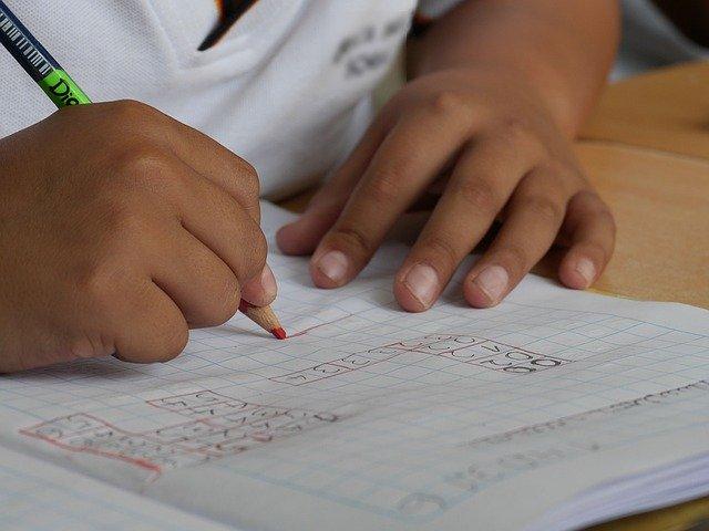 criança escrevendo em caderno na escola que reabriu após Covid-19