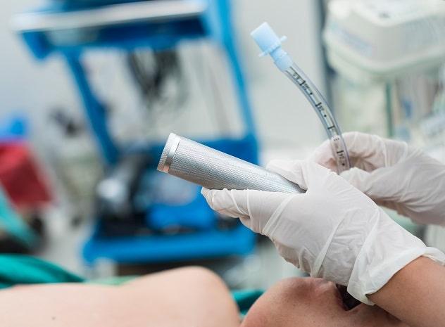 médico realizando intubação em paciente na emergência