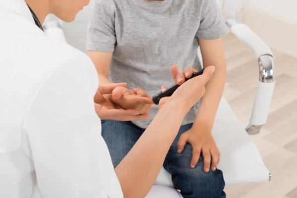 médico utilizando caneta de medição de açúcar no sangue em criança com diabetes