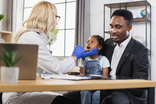médica consultando criança negra de outra etnia durante pandemia