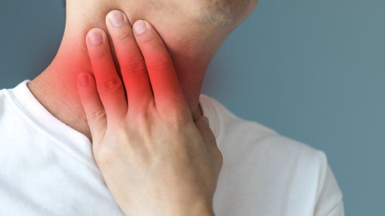 Homem sentindo dor de garganta, um dos sintomas de mononucleose infecciosa