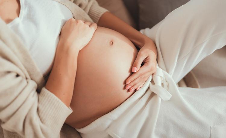 Mulher grávida deitada com a mão na barriga