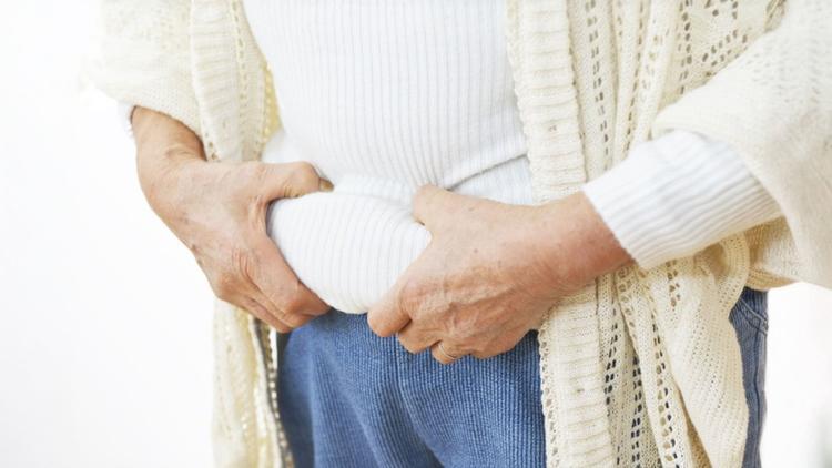 Mulher com obesidade na menopausa pressionando a barriga