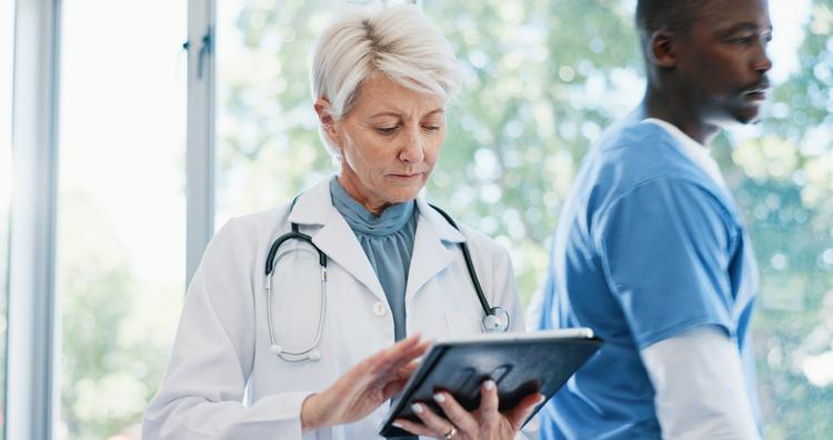 Healthcare, mature doctor and tablet for research on medical treatment, cure and scroll online. Hospital and woman oncologist and digital for report review, solution and planning for diagnosis.